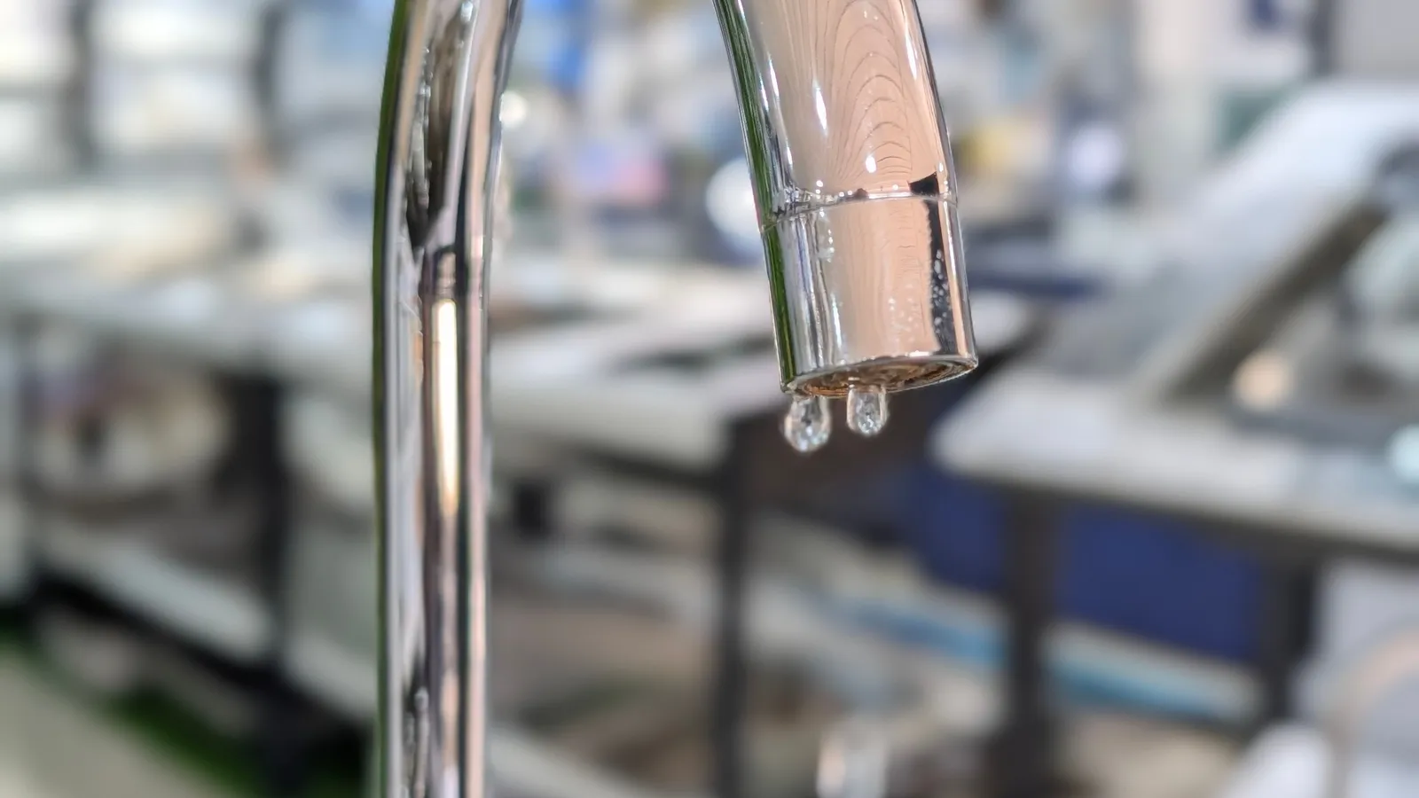 Grifería cromada con una gota de agua cayendo del pico aunque la llave está cerrada