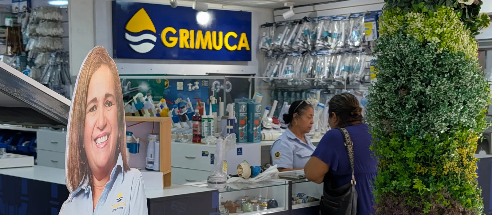 Vendedora atendiendo a una clienta en el mostrador de Grimuca, con el rótulo de la tienda al fondo